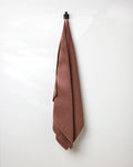 A GEOMETRY Dusty Rose Waffle Bath Towel hangs neatly from a black hook on a plain white wall.