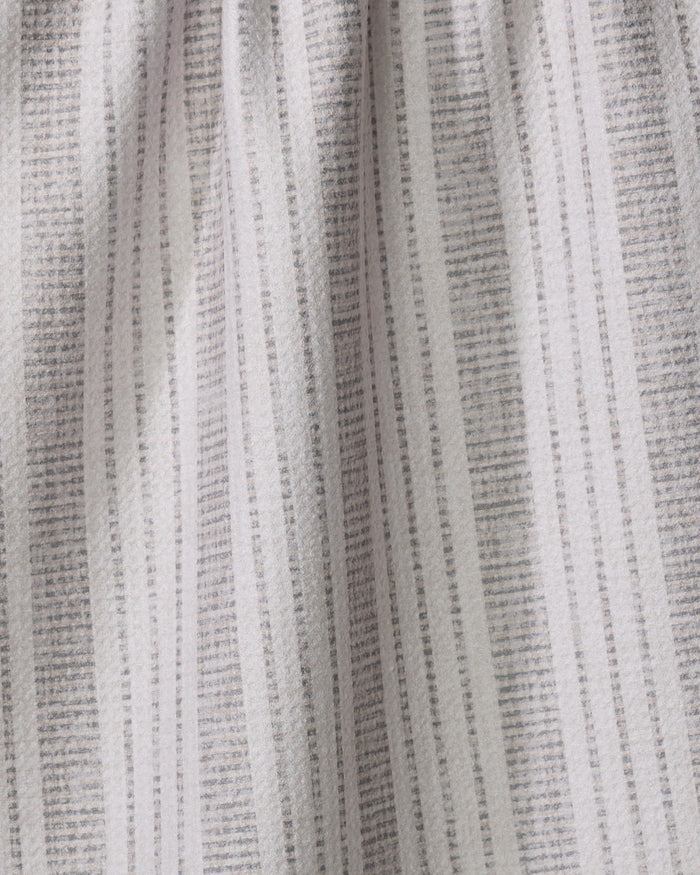 Close-up of the Becki Owens Dyer Grey kitchen tea towel, featuring light gray fabric with dark gray and thin white vertical stripes. Made from recycled materials for an eco-friendly, textured, and gathered look.