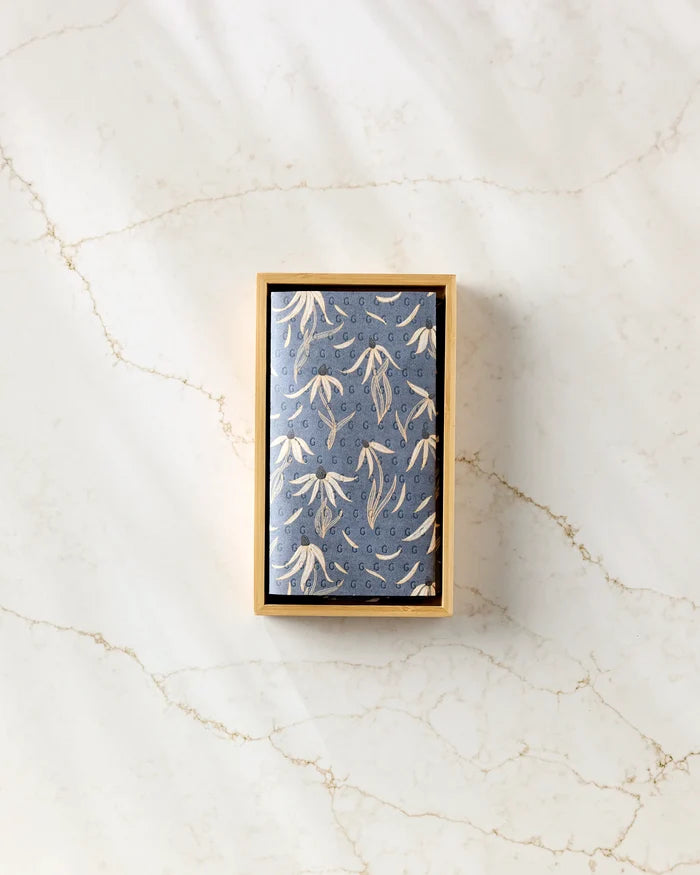 A rectangular box of Katie O'Shea Echinacea eco-friendly paper towels with a blue cover featuring white floral designs, displayed on a white marble surface with light brown veins.