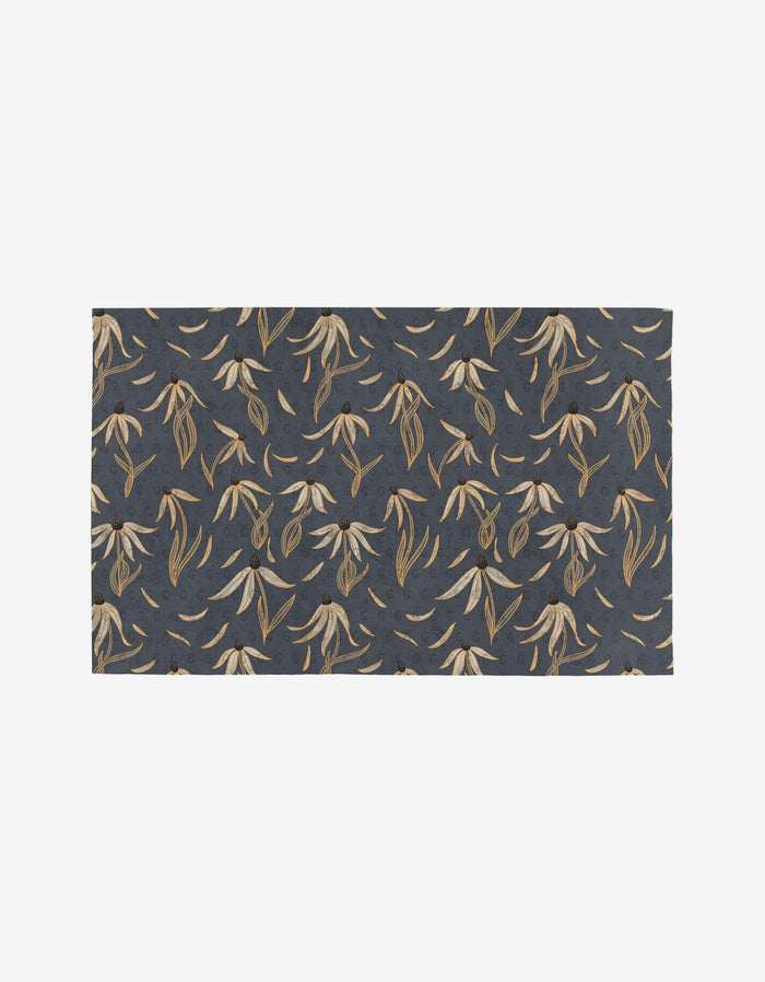 The Echinacea rug by Katie OShea features a dark blue background adorned with a repeating pattern of beige and light brown leaves, inspired by botanical elements and eco-friendly design.