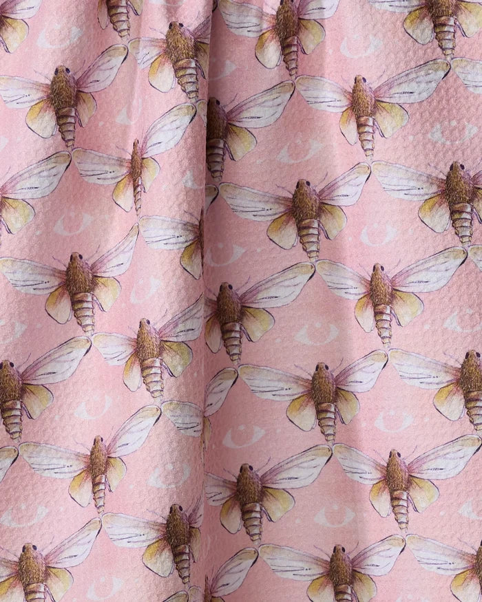 Echo by Maayan Alper-Swan: a pink Geoweave tea towel displaying detailed, realistic moths with outstretched wings and subtle crescent moon shapes in the background.