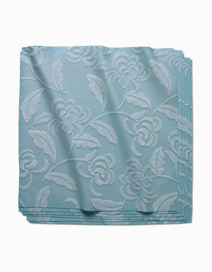 The GEOMETRY Ediths Embroidery Dinner Napkin Set in light blue features a subtle white floral and leaf pattern on eco-friendly Geosuede fabric, displayed neatly folded against a white background.