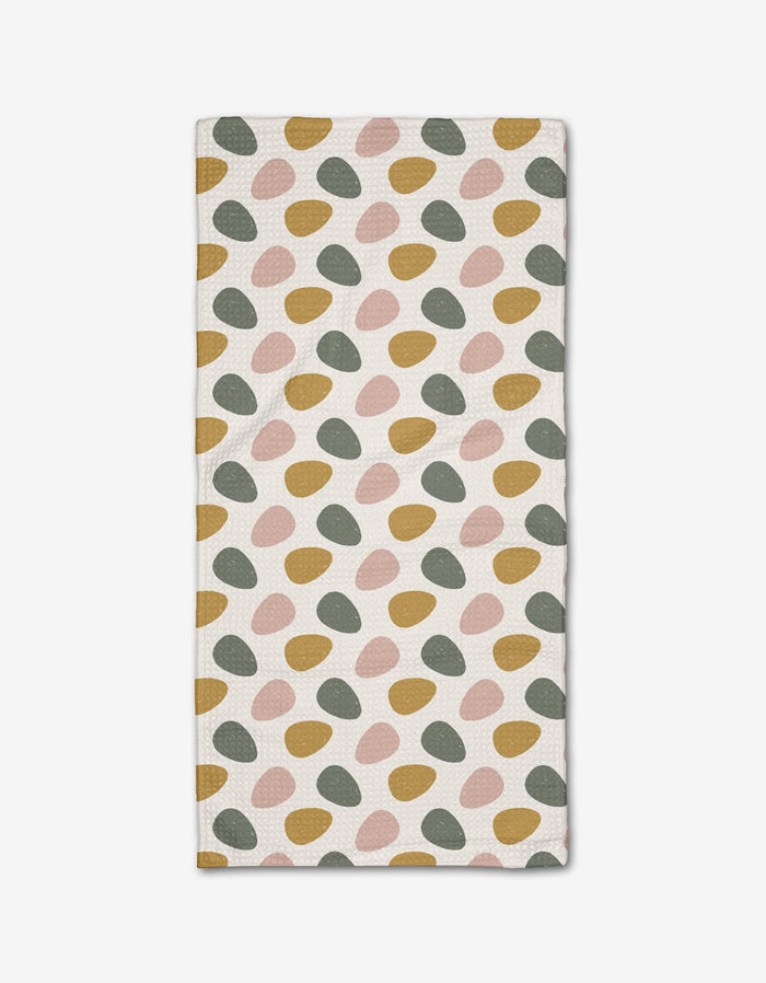 The Egg Hunt bar towel by Charlie Rowan Designs features irregular oval patterns in mustard yellow, blush pink, and sage green on soft Geoweave fabric, arranged in diagonal rows across a white background.