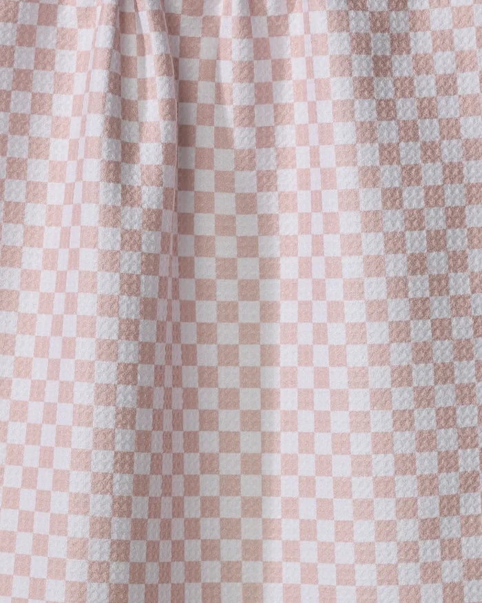 A close-up of the Ella quick-drying towel by Charlie Rowan Designs, featuring a pink and white checkerboard pattern and gentle vertical folds.