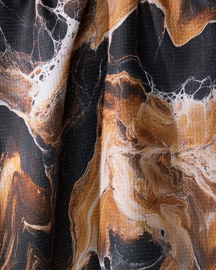 A close-up of Geometry’s Emperador tea towel showcases its absorbent material and marbled black, brown, and white pattern with swirling, stone-like textures and soft folds.