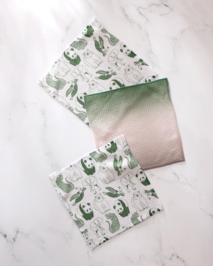 The GEOMETRY Endangered set features three reusable cloths: two with green animal prints (pandas, turtles, rabbits) and one pink cloth with a green gradient. Made from recycled materials for eco-friendly cleaning.