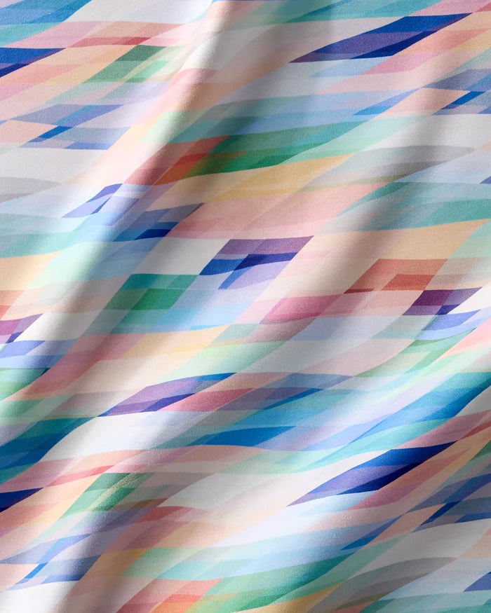 The Rachel Parker Eventide napkin set features eco-friendly fabric with a geometric pattern of overlapping pastel diagonal bands, adding a dynamic, abstract touch to your table while caring for the planet.