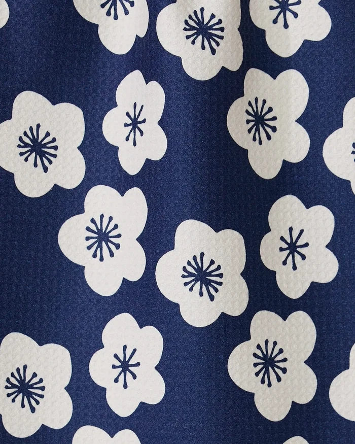 A close-up of GEOMETRYs Every Sunday kitchen towel showcases blue fabric with white floral patterns and dark blue centers. Its slightly pebbled texture adds style, while ultra-absorbency makes it perfect for daily use.