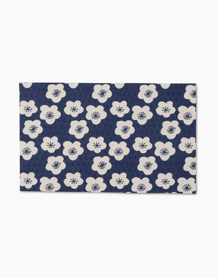 Every Wish by GEOMETRY is a rectangular, reusable mat featuring white flowers with dark centers on a navy blue background, along with subtle circular motifs—an eco-friendly alternative to Not Paper Towels.