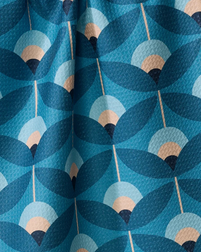 The Fall Florals tea towel by Blissful Flamingo is crafted from recycled materials and showcases a retro, mid-century modern pattern of stylized leaves and semi-circles in blue, cream, and dark navy with textured folds.