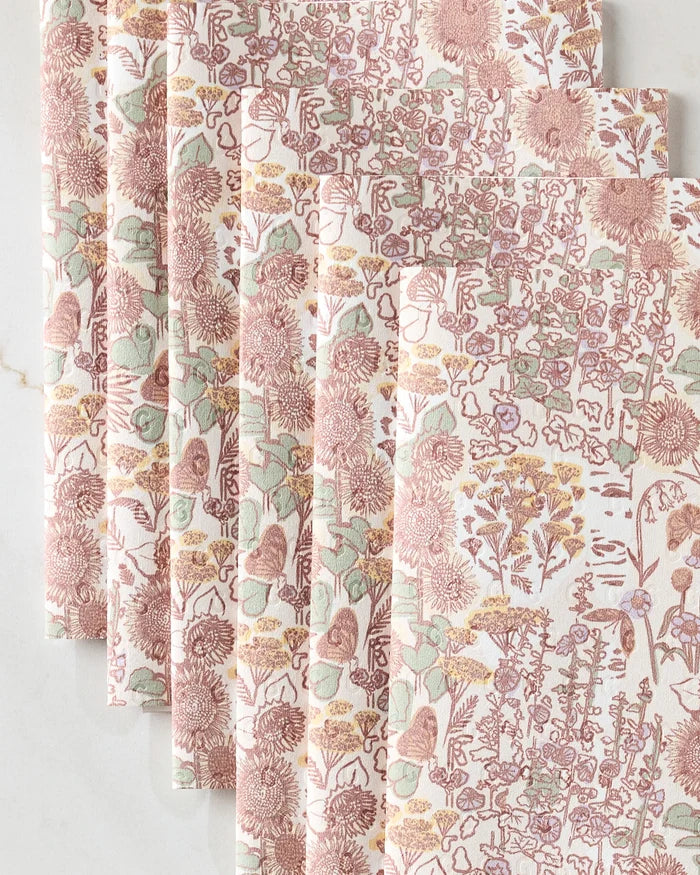 Five folded, reusable paper towels from Elisabeth Wing’s Fall Forest collection are stacked on a light marble surface. Their intricate floral and leafy design in pink, yellow, and green adds eco-friendly style to your kitchen.