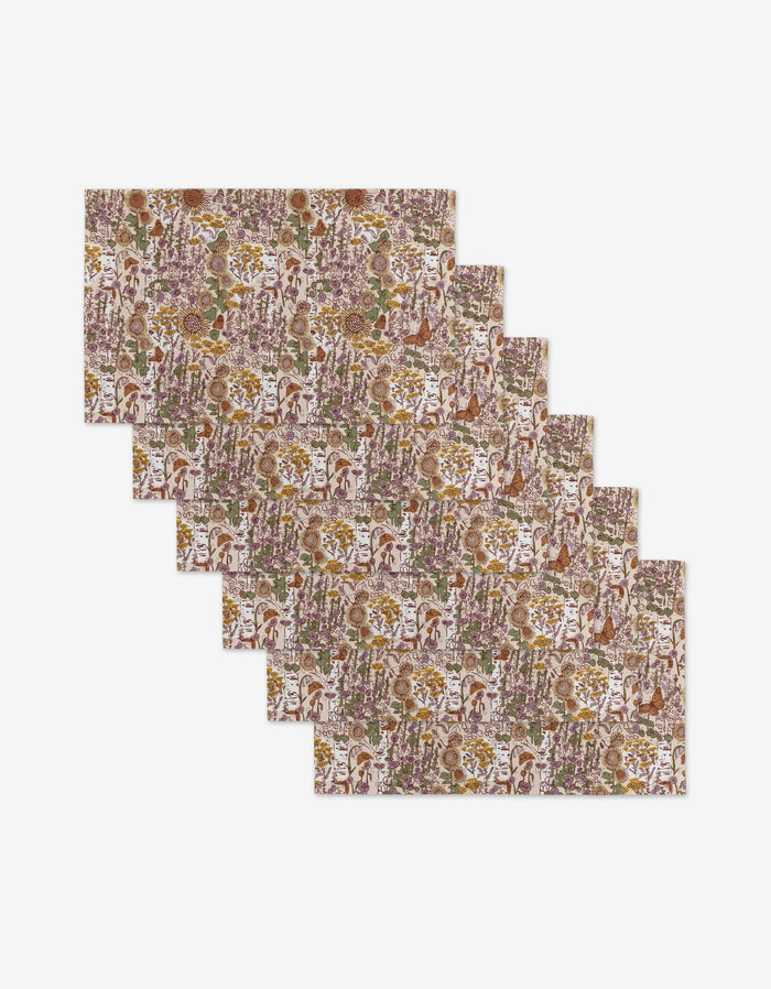 Six “Fall Forest” placemats by Elisabeth Wing, featuring a colorful floral and leaf pattern in brown, green, purple, and yellow, are arranged overlapping on white—an eco-friendly choice for your table.