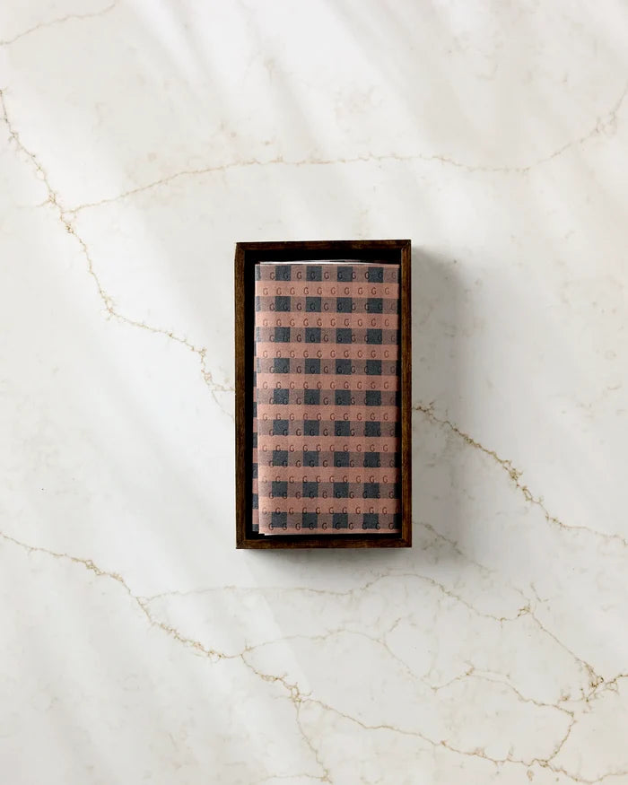 A rectangular Fall Gingham box by GEOMETRY, featuring a patterned two-tone design—ideal for storing eco-friendly kitchen towels—sits atop a white marble surface with light brown veins.