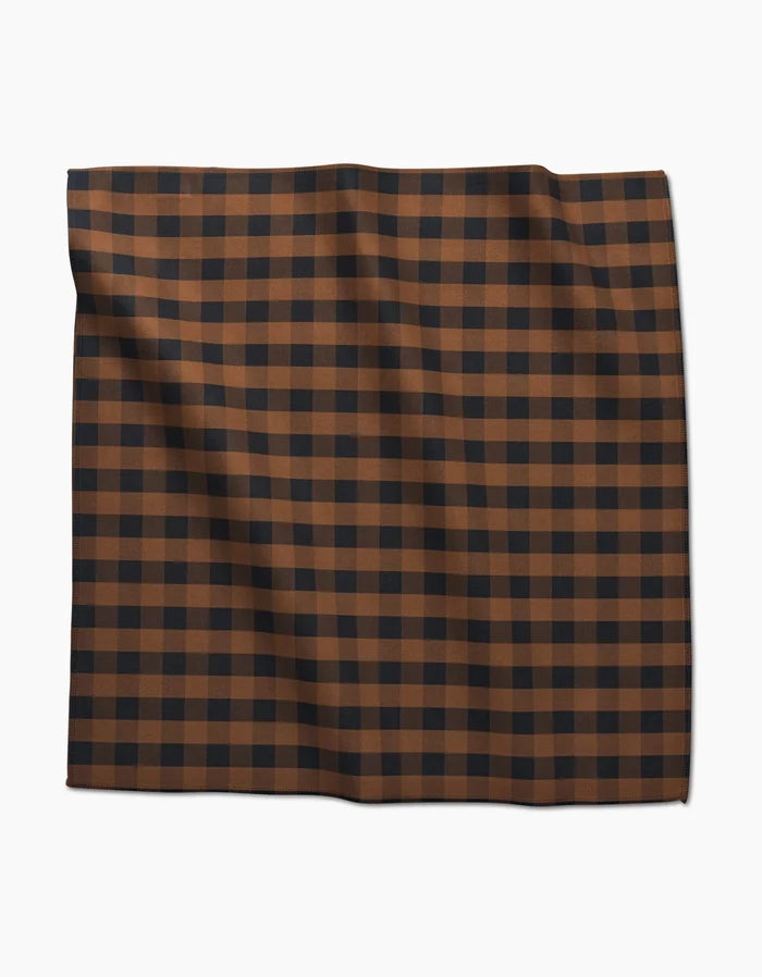 The GEOMETRY Fall Gingham Dinner Napkin features a brown and black checkered grid pattern on soft Geosuede fabric, displayed folded against a white background.