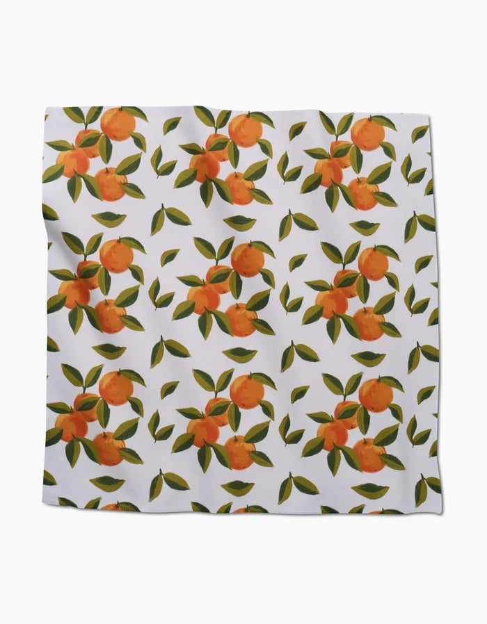 The GEOMETRY Fallbrook Oranges Dinner Napkin Set features white Geosuede fabric with a repeating pattern of orange fruits and green leaves in clusters, evenly scattered across each napkin.