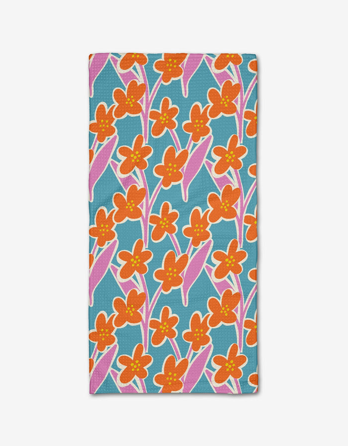 The Fancy Flowers Bar Towel by Lizzie Clark features a vibrant floral pattern with orange and yellow flowers and pink-accented leaves on teal blue Geoweave fabric, offering ultra-absorbency and a cheerful, lively look.