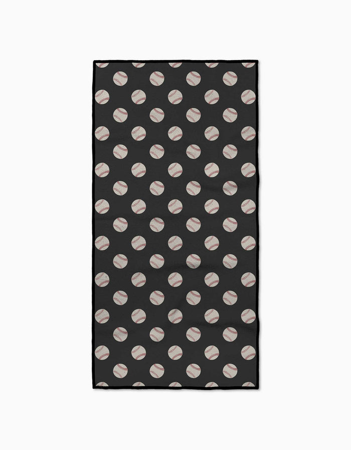 The Geometry Fastball Fitness Towel is a rectangular black towel featuring a repeating diagonal pattern of white baseballs with red stitching, made from ultra-absorbent recycled materials.