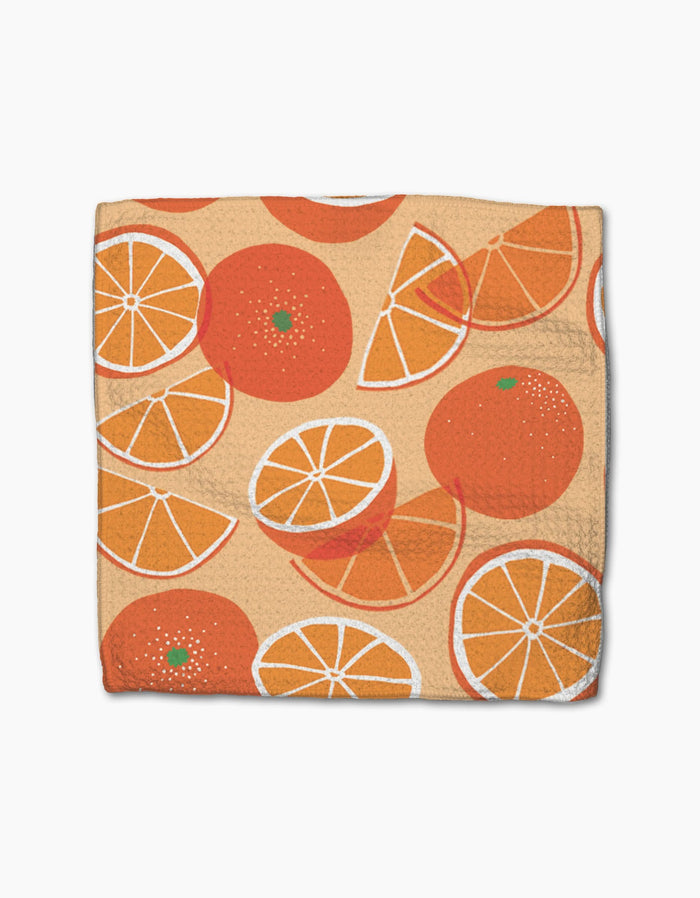 The Favorite Fruit dishcloth by Geometry features a beige Geoweave fabric with scattered orange and white illustrations of whole and sliced oranges, creating a bright, fresh look.