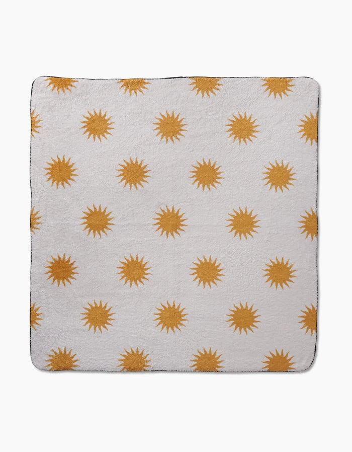 The Geometry Feeling Sunny blanket is a soft white square throw with a repeating yellow sun pattern, crafted from recycled materials for eco-friendly comfort.