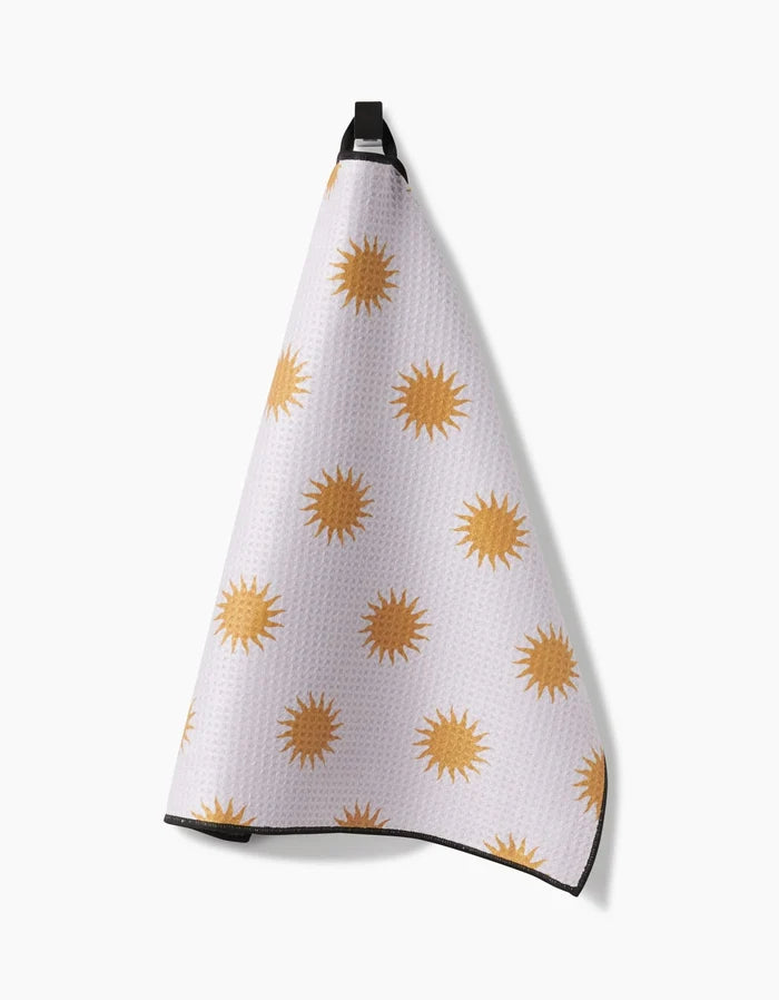 The Geometry Feeling Sunny towel, made from ultra-absorbent Geoweave fabric, features yellow sun shapes on a white background and hangs from a black loop.