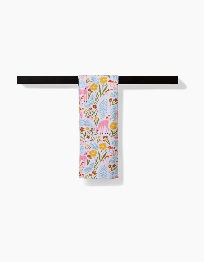 The Kayla Ann Fern and Fawn Bar Towel, featuring floral and animal patterns on Geoweave fabric, hangs neatly on a black horizontal bar against a plain white background.