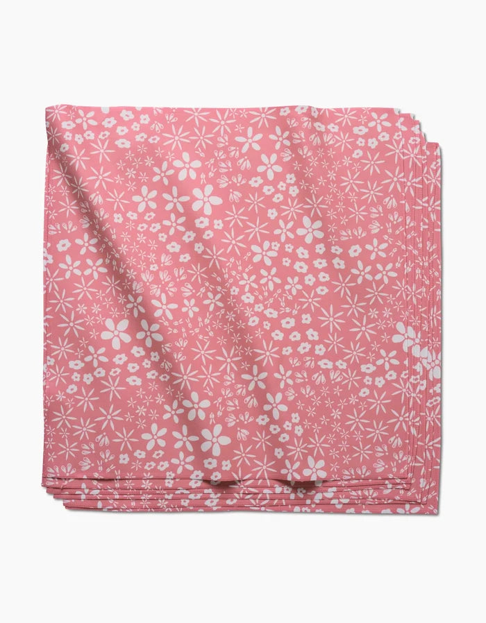 Field of Flowers by Hufton Studio: a folded pink geosuede dinner napkin with a white floral pattern of assorted small flowers, shown on a white background.