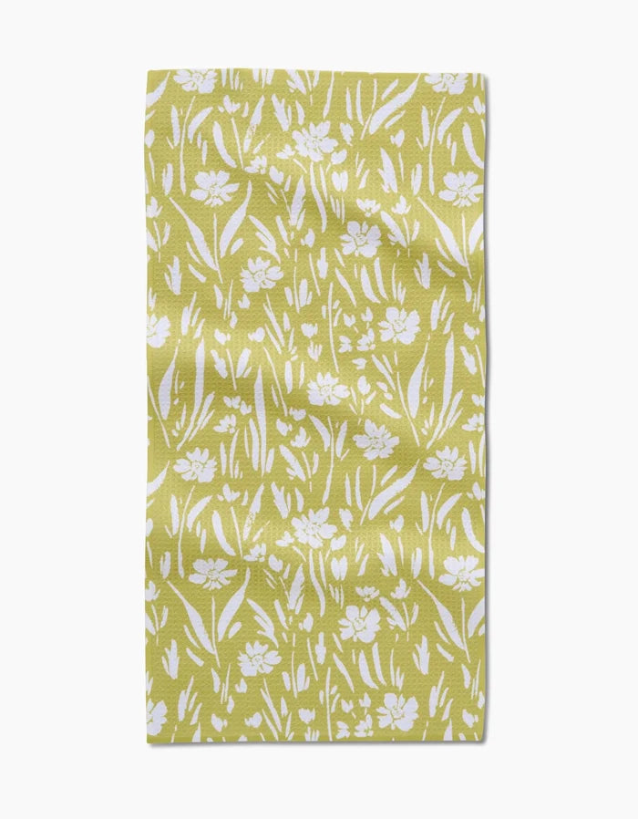 The Ashley Celena Field of Wildflowers Bar Towel is a yellow rectangular towel with a white floral and leaf pattern in various sizes on textured Geoweave fabric for a natural, slightly wrinkled look.