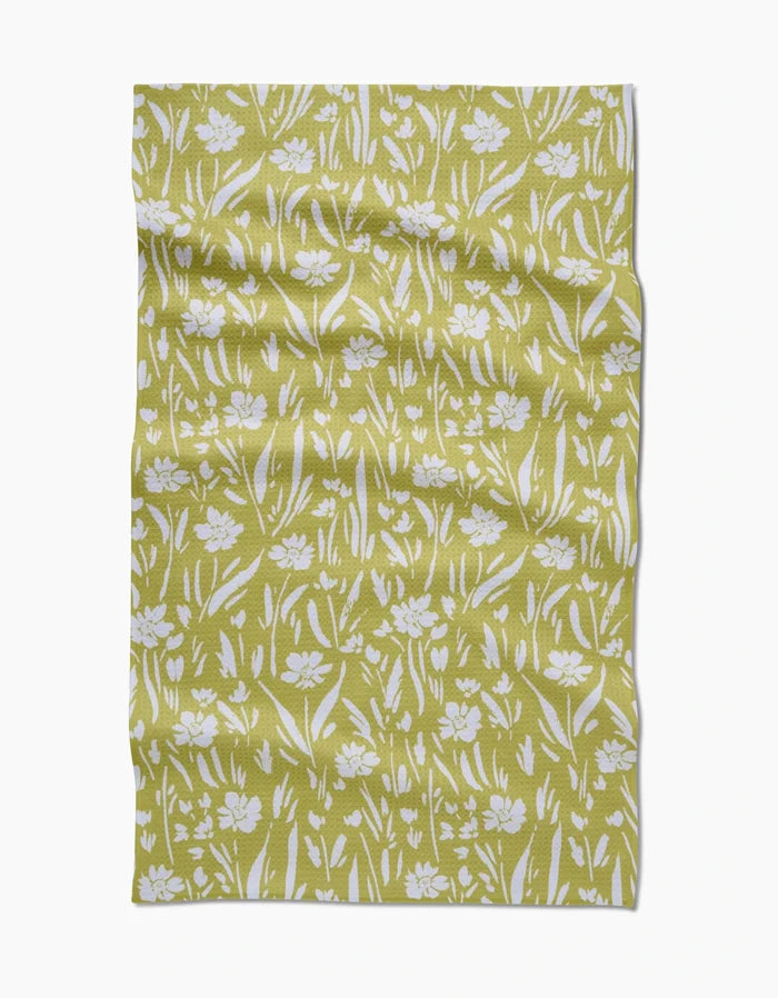 The Ashley Celena Field of Wildflowers Geoweave fabric features a yellow-green backdrop with white floral and grass designs. Ultra-absorbent and made from recycled materials, it offers eco-friendly style in every detail.