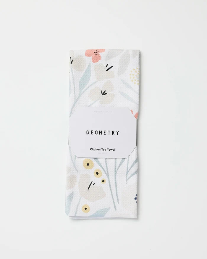 A folded white ultra-absorbent kitchen towel with a subtle floral pattern in soft pastels, labeled "Amy MacCready Fiona Cream," made from recycled materials and set against a plain white background.