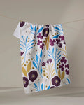 The Fiona Dark Maroon kitchen towel by Amy MacCready hangs on a clothesline, showcasing its deep maroon floral pattern against a neutral background.