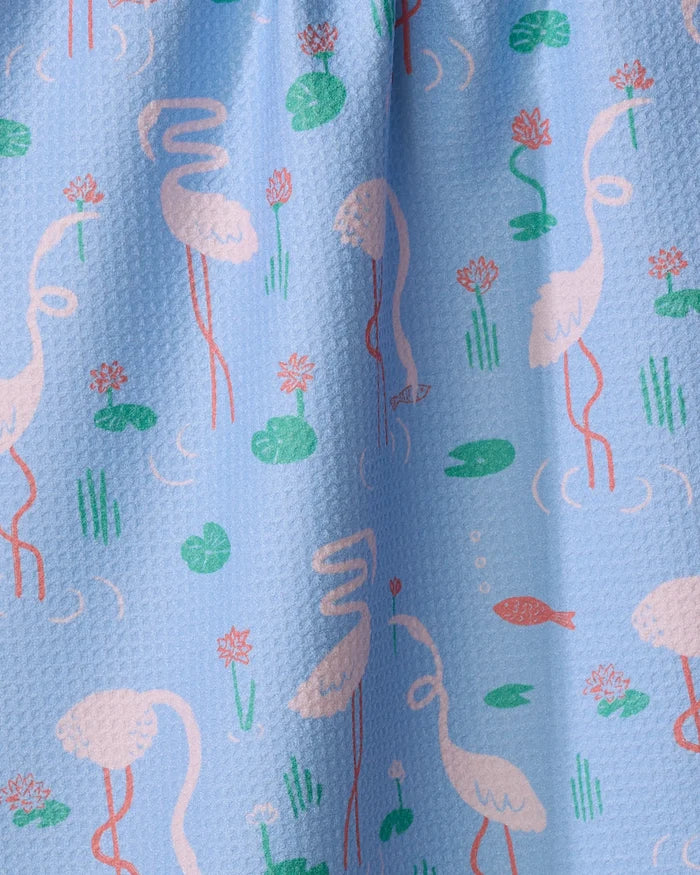 The Flirty Flamingo tea towel by Elisabeth Wing showcases pink flamingos, lily pads, grasses, water ripples, lotus flowers, and an orange fish on light blue. Made from ultra-absorbent recycled materials.