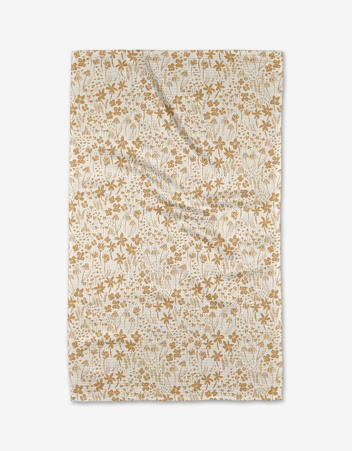 The Floating Meadow tea towel by Hufton Studio features an intricate golden brown floral pattern on beige Geoweave fabric, shown laid flat against a white background.