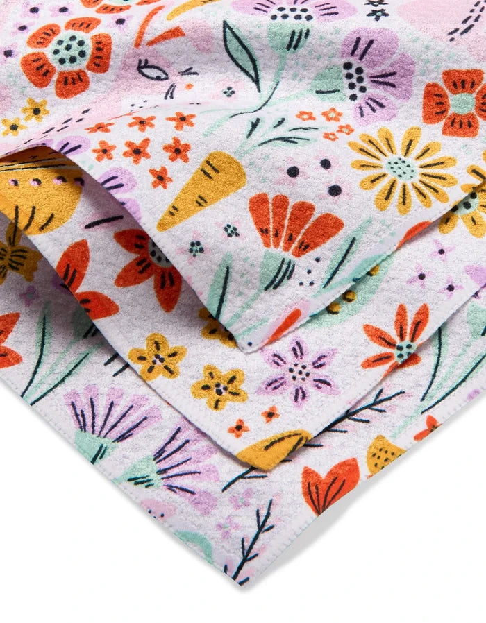 Floppsie Lilith and Thaddeus dishcloth set by Amy MacCready features folded white towels with a vibrant floral pattern in red, yellow, orange, and purple. Made from recycled materials for an eco-friendly, cheerful touch.