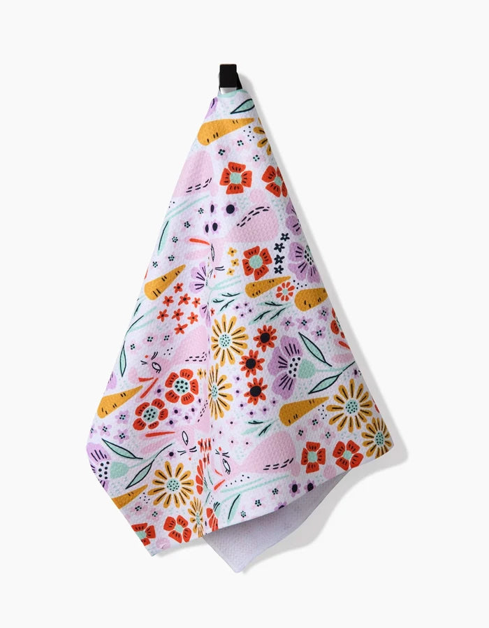 Floppsie by Amy MacCready: A pastel pink tea towel with yellow, red, and purple floral and green leaf print, plus a black hanging loop. Made from quick-drying recycled materials for stylish, sustainable use.