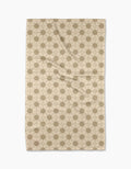 The Geometry Flora Tile Tea Towel is a beige rectangular towel with a repeating hexagon and interlocking circle pattern in light brown, displayed flat on a white background. Made from premium Geoweave fabric for superior absorbency and softness.