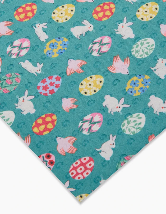 The Floral Easter Garden by Ceyda Alasar is a teal reusable paper towel featuring colorful eggs, white bunnies, and pink birds—ideal for eco-friendly kitchens. The image displays the towel angled with its bottom left corner in view.