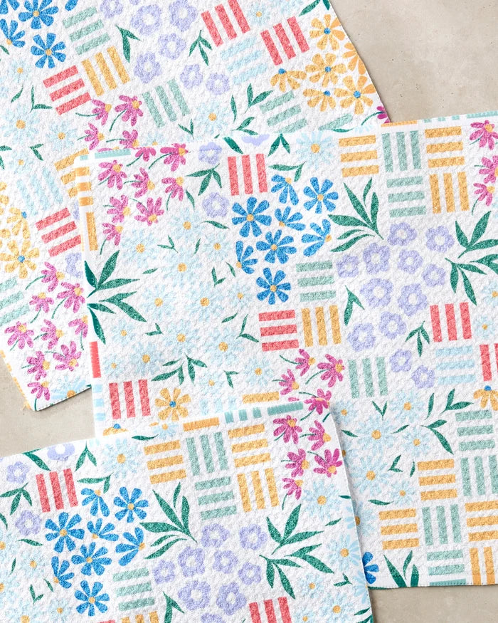 Floral Garden paper towels by Charlie Rowan Designs, made from recycled materials, feature textured surfaces with pink, blue, yellow, and green floral and geometric patterns overlapping on a light beige background.