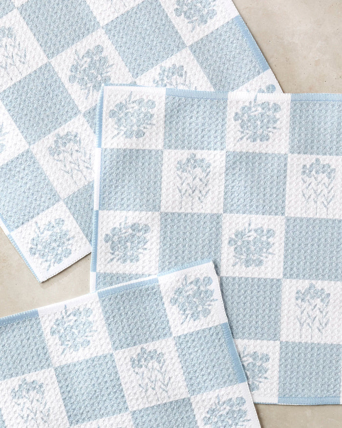 Four Charlie Rowan Designs "Floral Patchwork" dish towels, featuring blue and white checks with subtle florals and made from recycled materials, are slightly overlapped on a light surface.