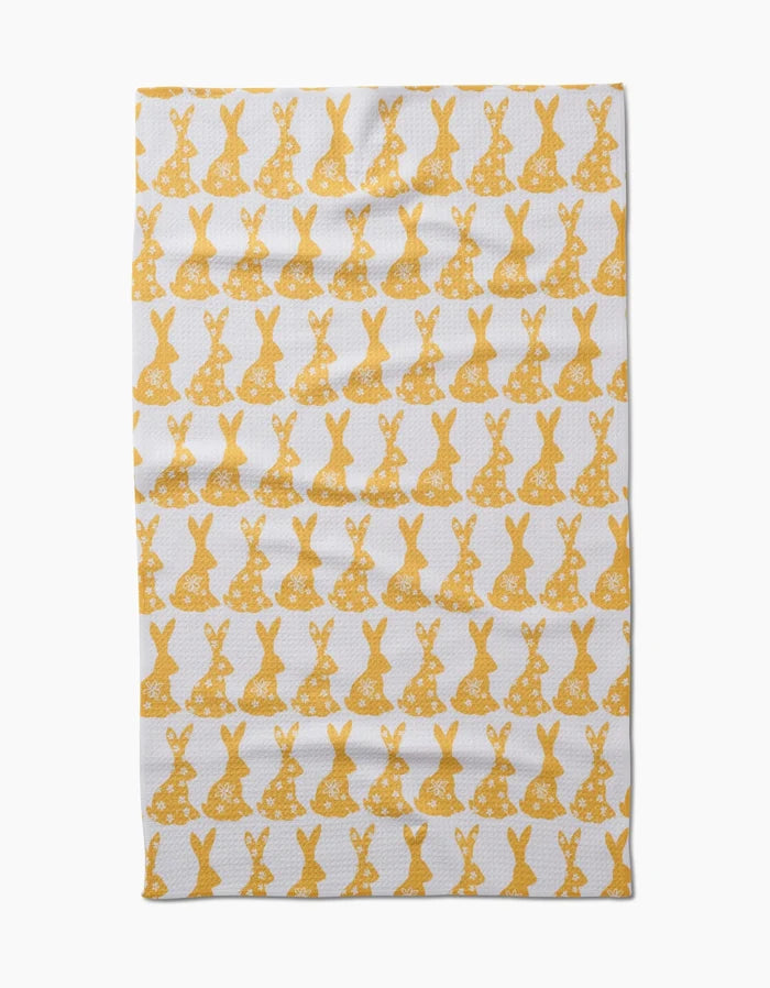 The Hufton Studio Floral Spring Bunny tea towel is ultra-absorbent and white, featuring neat horizontal rows of yellow bunny silhouettes with floral designs across the entire surface.