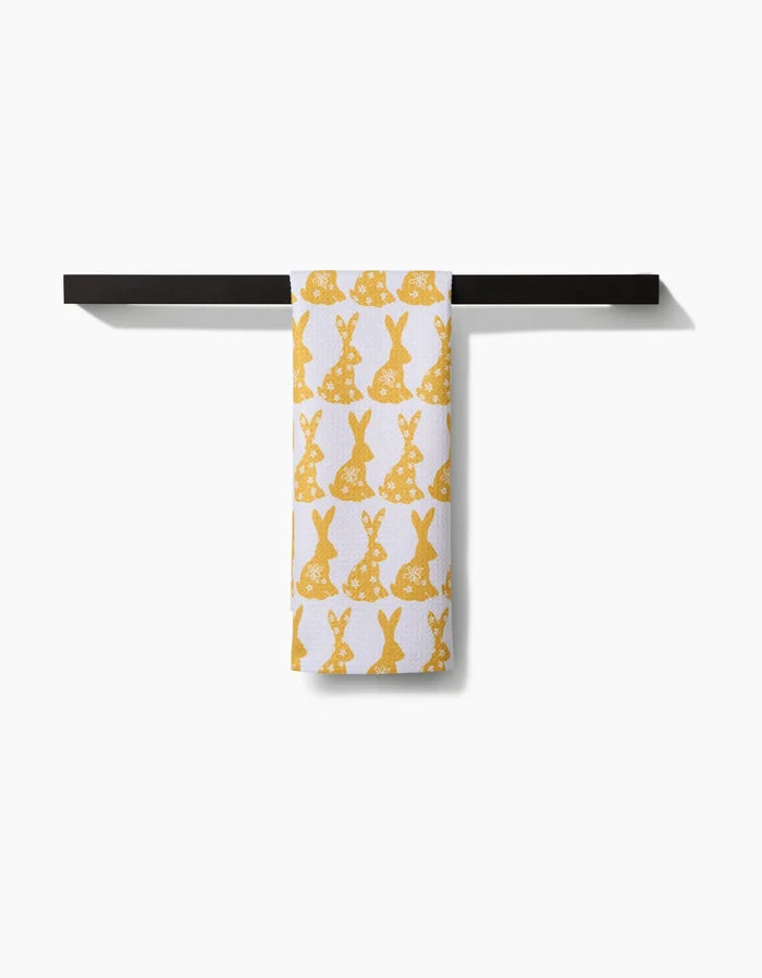The Hufton Studio Floral Spring Bunny towel, featuring yellow bunny silhouettes, hangs neatly on a black towel bar against a white background.