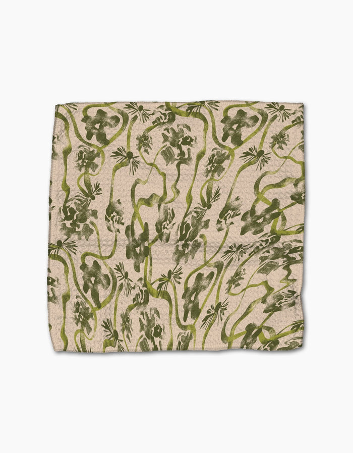 Geometry’s “Floral Swirls Green” dishcloth is square, beige, and made from recycled materials, featuring an abstract green jungle pattern with vines, leaves, and playful monkeys.