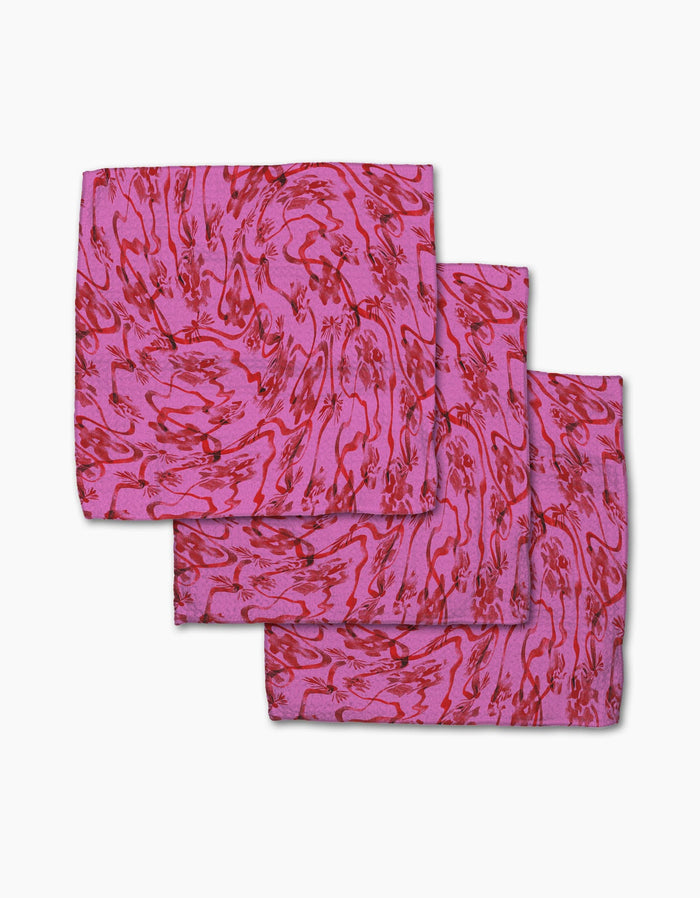 Three folded Geometry Floral Swirls Pink napkins made from Geoweave fabric, featuring a red abstract pattern, are arranged overlapping on a white background.