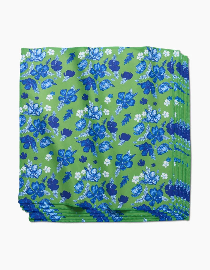The Flower Bomb Dinner Napkin Set by GEOMETRY features folded green Geosuede fabric with a blue and white floral pattern, crafted from recycled materials for an eco-friendly and stylish table setting.
