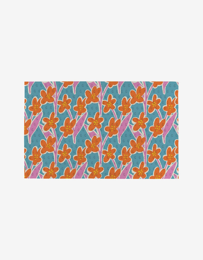 Flower Parade by Lizzie Clark features orange flowers with pink leaves and stems on a blue background with light blue swirls—a vibrant, eco-friendly decor choice.
