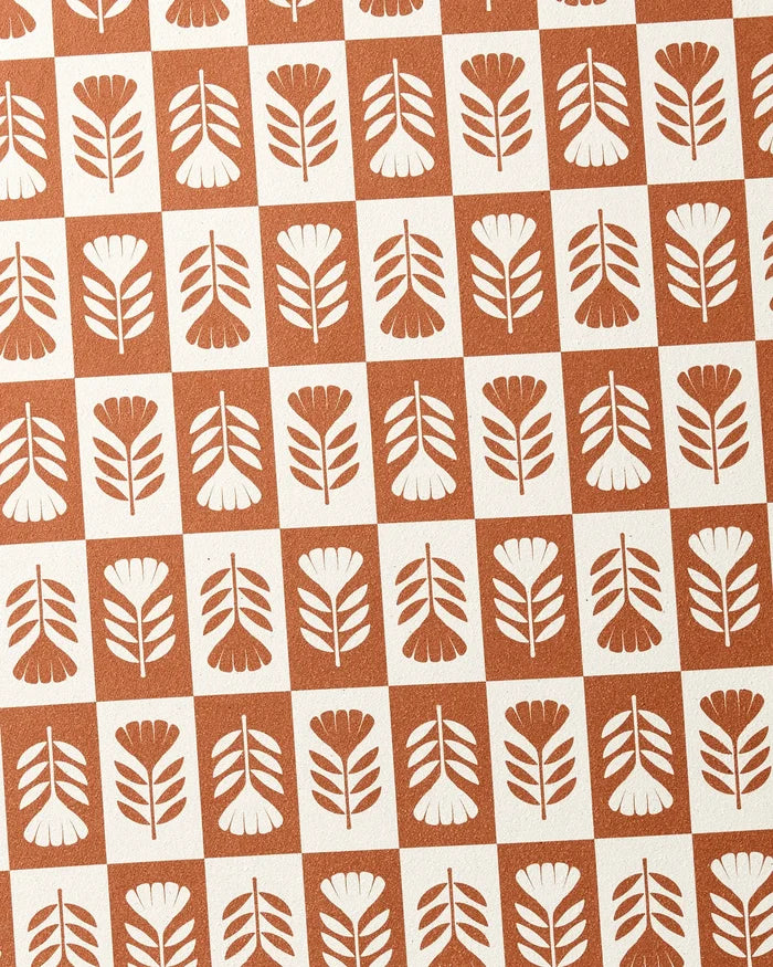 The Flower Patch yoga towel by Charlie Rowan Designs features a retro, symmetrical design with brown and white squares, each displaying a simple flower or leaf motif, all crafted on recycled material.
