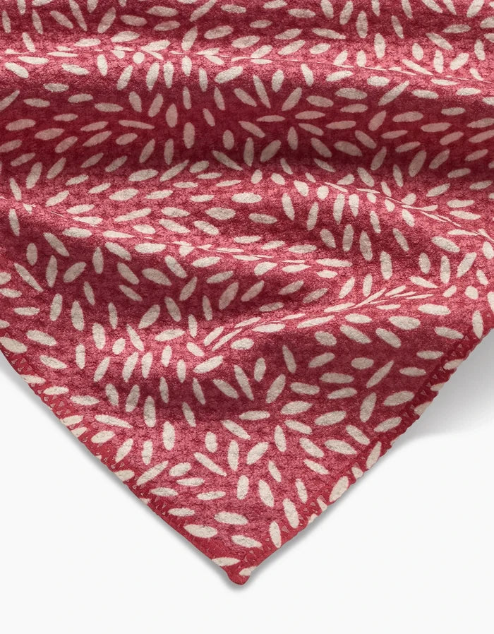 A close-up of Amita Nair’s Flower Seeds packaging in red, featuring small white oval shapes. The stylish branding is visible in the lower corner, and the package fabric shows slight wrinkles for added texture.