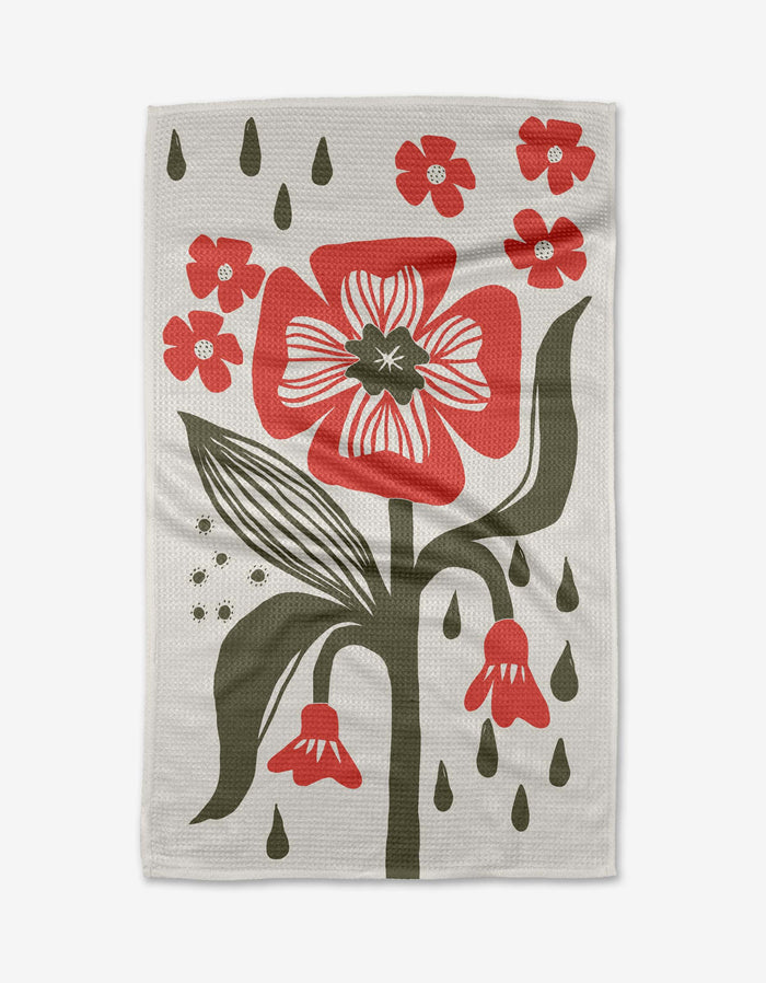 The Ash Cascade Flower Stamp tea towel is white and textured, featuring a bold red flower with green leaves, smaller red flowers, green accents, and teardrop-shaped details.