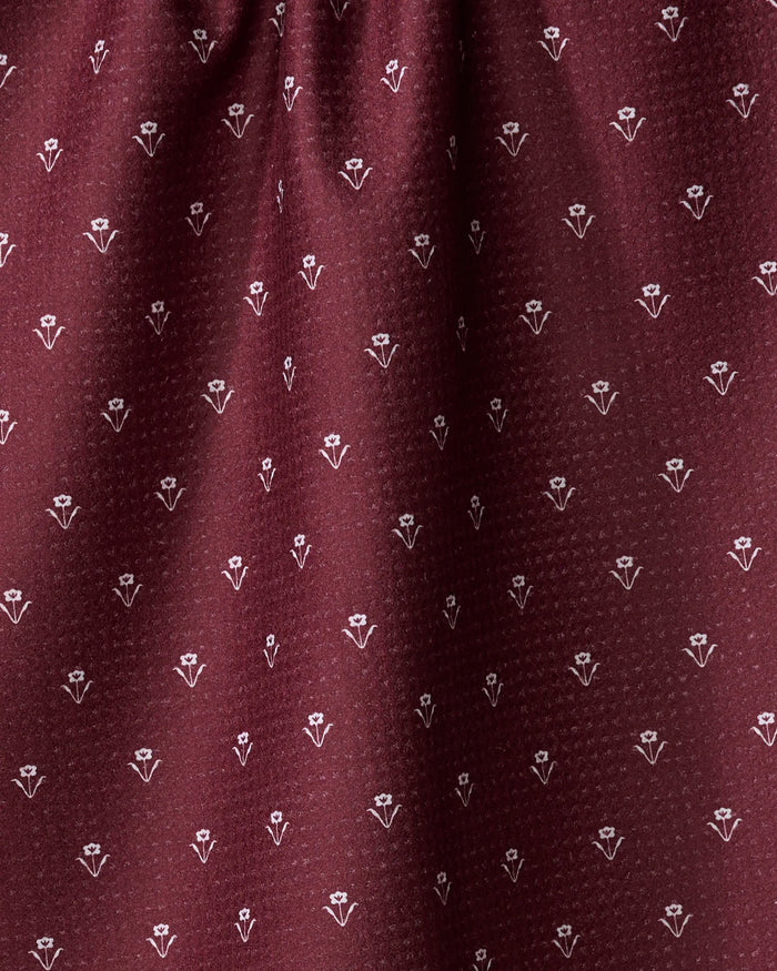 Close-up of the Flowerfield Wine fabric by The Buy Guide, featuring maroon dotted texture with repeating white floral motifs—an absorbent, eco-friendly dish towel perfect for daily kitchen use.