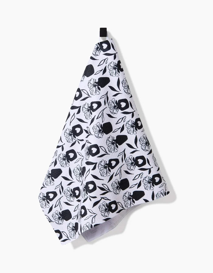 The Flowers for Me tea towel by Charlie Rowan Designs features a quick-drying white fabric with a black floral and leaf pattern, hanging from a black loop against a plain white background.