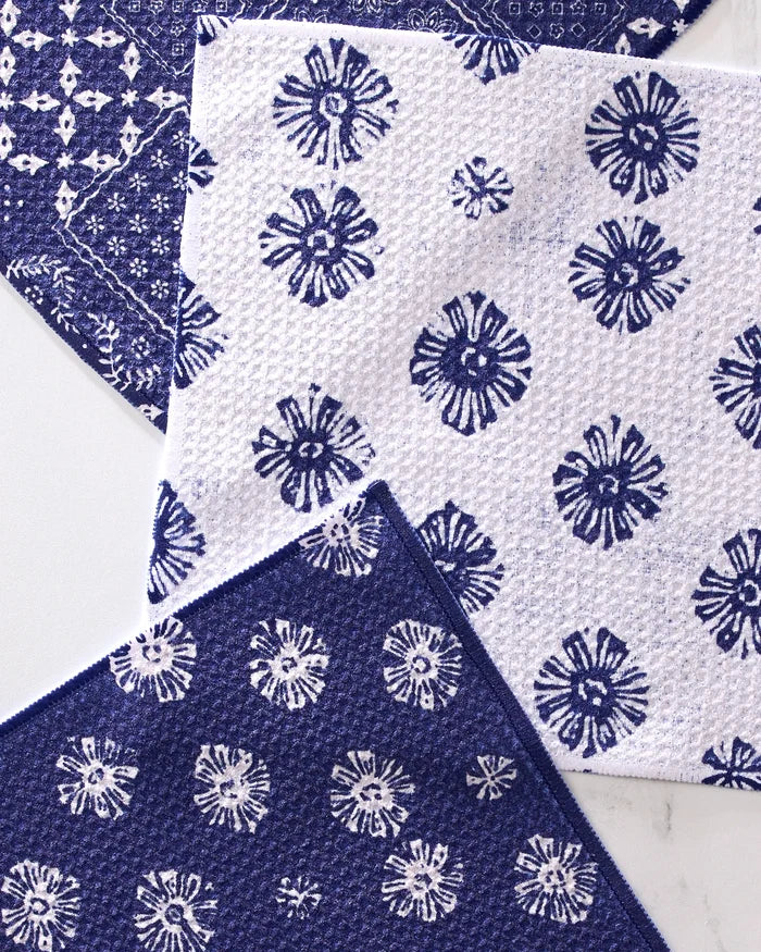 The Geometry Flowing Ocean dishcloth set includes four super-absorbent towels made from recycled materials, each featuring blue and white geometric flower patterns in alternating designs.